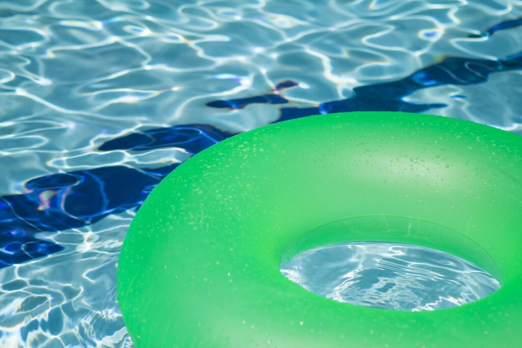 Outdoor Pool A vibrant green inflatable swim ring floating in a refreshing blue swimming pool.